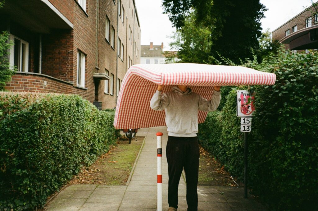 a man carrying a mattress while looking for packers and movers